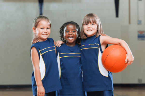 Three young girls smiling and holding a basketball